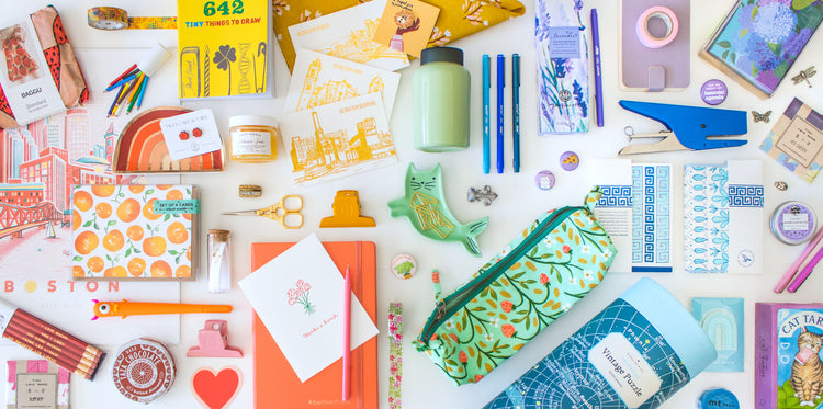 rainbow assortment of stationery and gift products including letterpress greeting cards, staplers, pencil pouches, books, chocolate, puzzles, pins, pens, candles, washi tape, ring dishes, prints